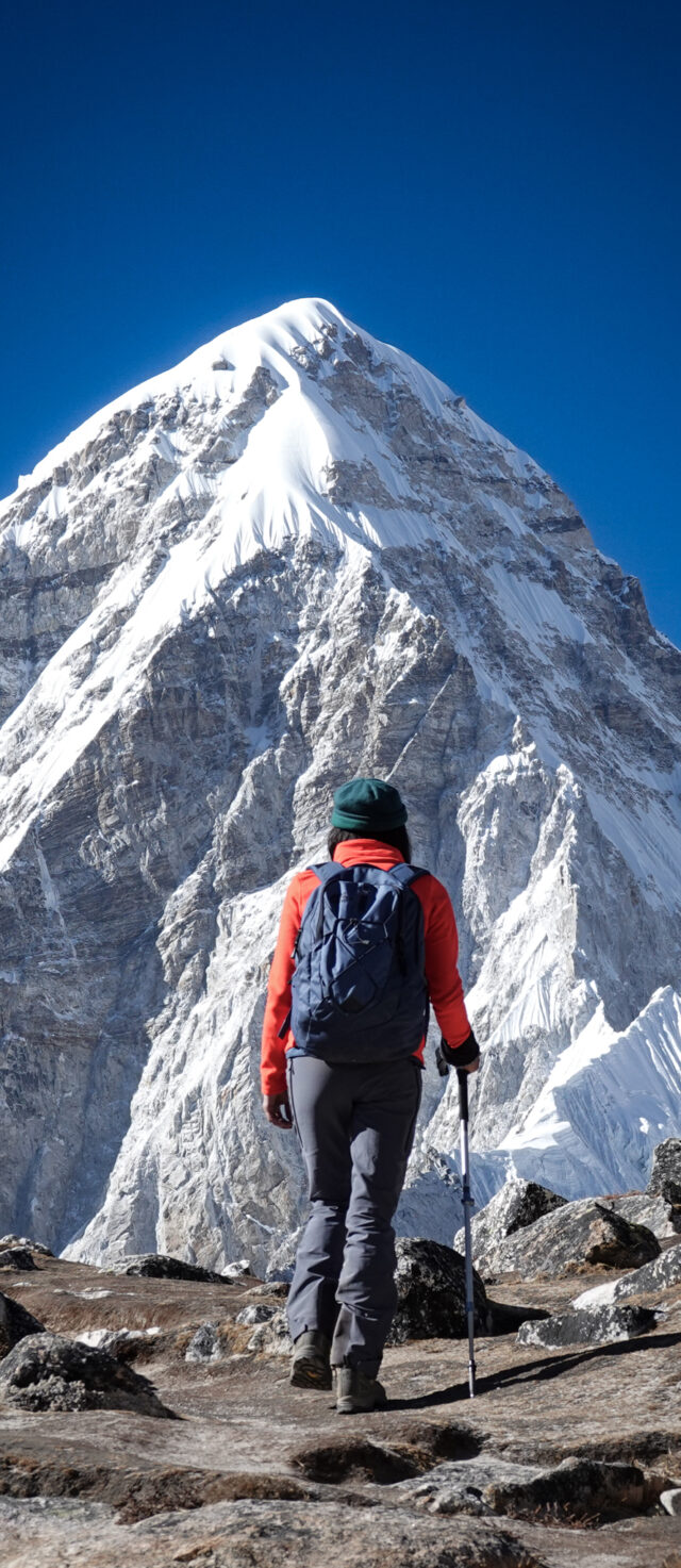 Trekker approaching a high Himalayan peak on a mountain trail in Nepal