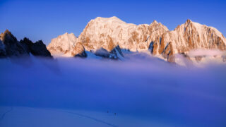 Sunrise light on snowy alpine peaks above cloud in the Mont Blanc massif