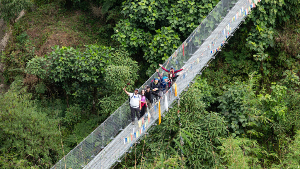 Small group crossing a suspension bridge during a guided mountain trekking adventure