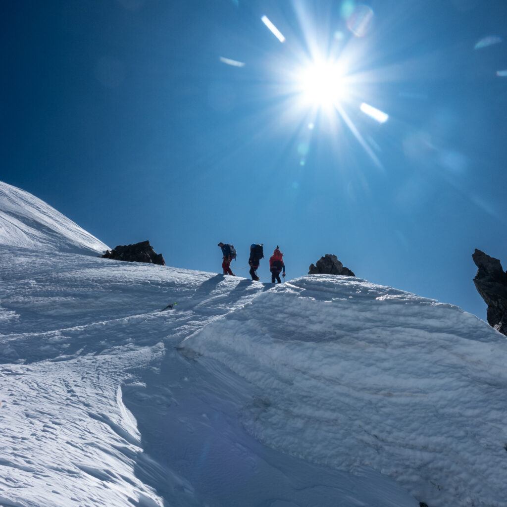 Rope team climbing high on Mont Blanc under clear skies during the final ascent