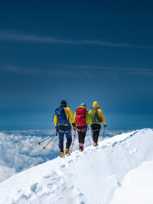 Three climbers on the exposed upper ridge of Mont Blanc during a guided ascent.