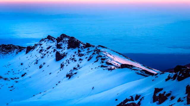 Snowy high alpine landscape on Kilimanjaro at dawn with climbers on the route.