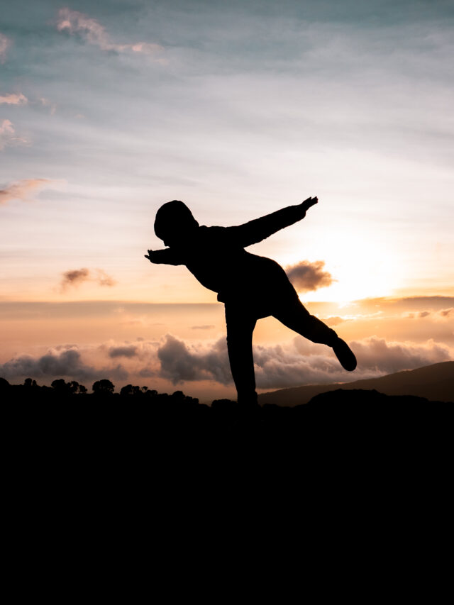 Silhouette of a person at sunset on Kilimanjaro with clouds and mountain ridges in the background.