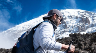 Trekker hiking below the snow covered upper slopes of Mount Kilimanjaro.