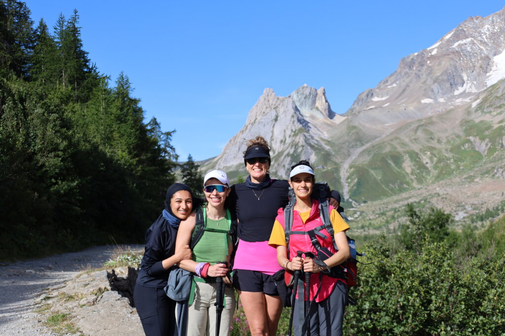 Group of hikers on the Tour du Mont Blanc trail near Courmayeur with alpine mountains behind