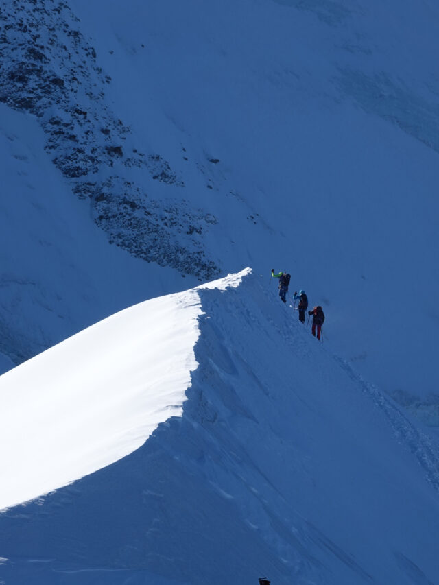 Three climbers moving carefully along a steep snow ridge on Mont Blanc.