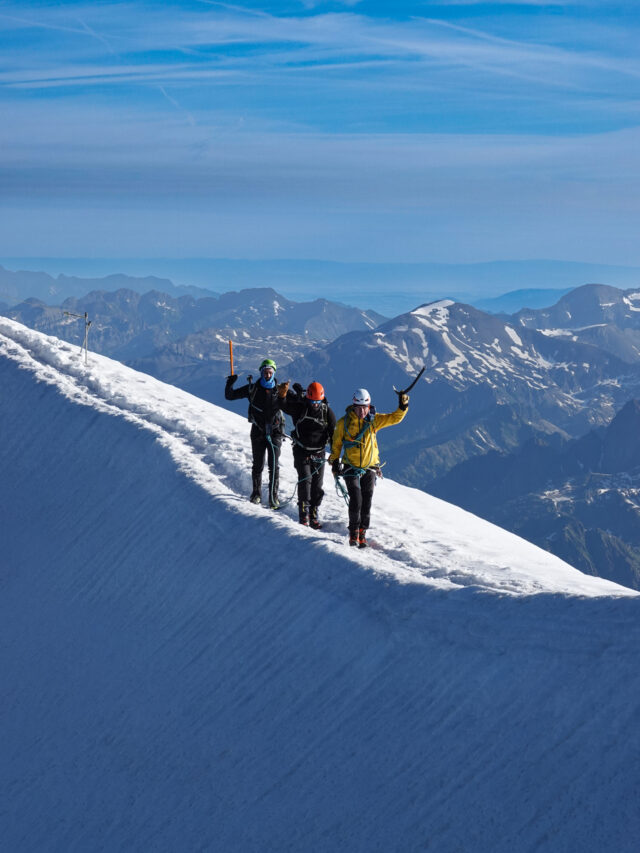 Climbers walking the snowy ridge toward a high mountain hut on Mont Blanc.