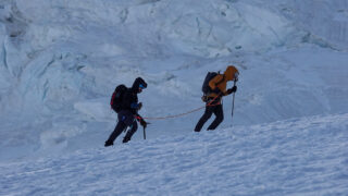 Roped climbers moving steadily up a snowy glacier slope on Mont Blanc.