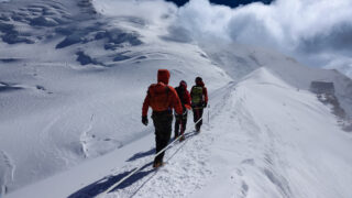 Climbers following the narrow summit ridge of Mont Blanc above the cloud layer.