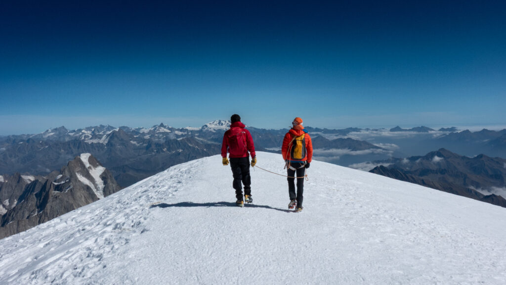 Two climbers standing on the Mont Blanc summit after ascending via the Goûter Route