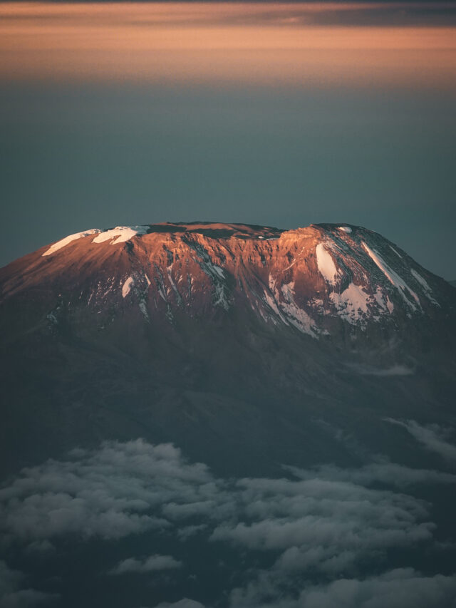 Sunrise light hitting the upper slopes of Mount Kilimanjaro above the cloud layer.