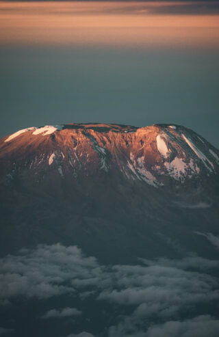 Sunrise light hitting the upper slopes of Mount Kilimanjaro above the cloud layer.