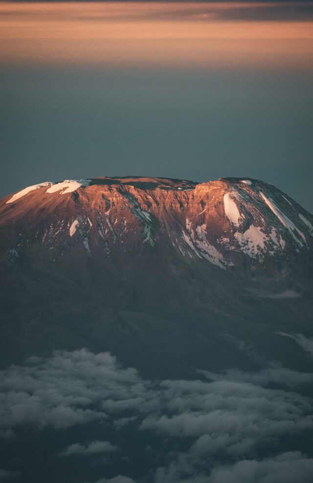 Sunrise light hitting the upper slopes of Mount Kilimanjaro above the cloud layer.