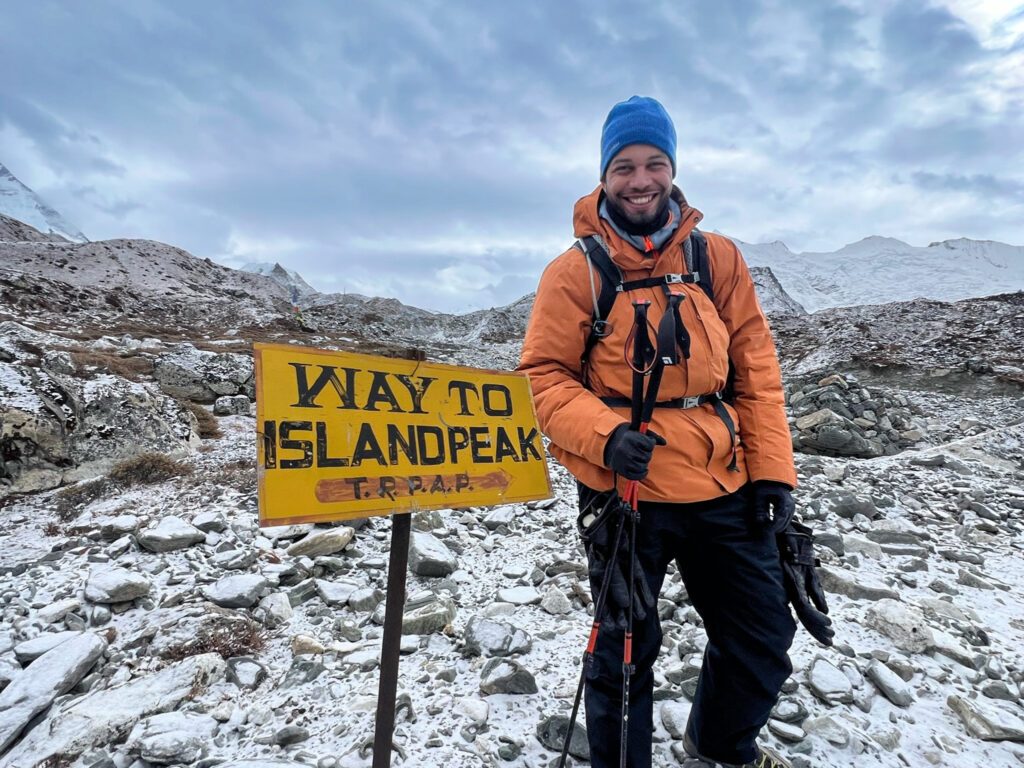 Trekker near Island Peak trail sign in snowy Nepal conditions showing winter trekking atmosphere
