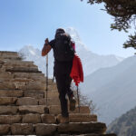 Trekker walking up stone steps toward Himalayan mountain views on the Everest Base Camp trail