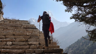 Trekker walking up stone steps toward Himalayan mountain views on the Everest Base Camp trail