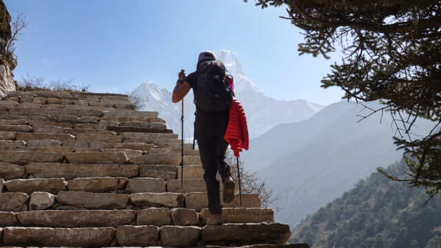 Trekker walking up stone steps toward Himalayan mountain views on the Everest Base Camp trail