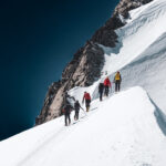 Climbers ascending a snowy alpine ridge on Mont Blanc during the summer climbing season with Life Happens Outdoors.