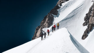 Climbers ascending a snowy alpine ridge on Mont Blanc during the summer climbing season with Life Happens Outdoors.
