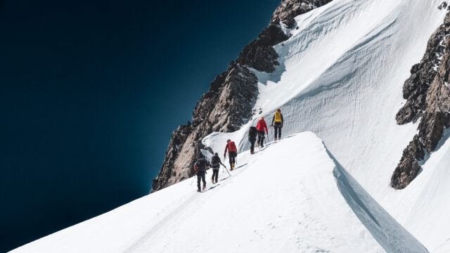 Climbers ascending a snowy alpine ridge on Mont Blanc during the summer climbing season with Life Happens Outdoors.