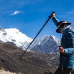Trekker using poles beneath snow covered Himalayan peaks on the Everest Base Camp route in Nepal