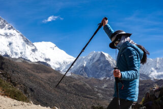 Trekker using poles beneath snow covered Himalayan peaks on the Everest Base Camp route in Nepal