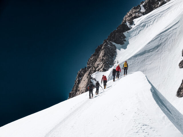 Climbers ascending a snow ridge on Mont Blanc during a guided Life Happens Outdoors expedition, illustrating the time and preparation needed for the climb.