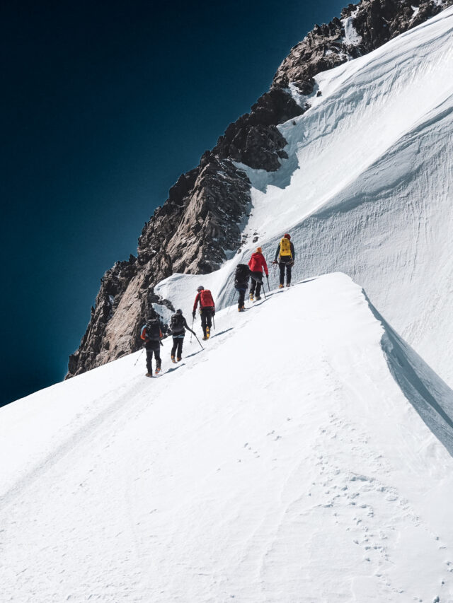 Guided team climbing toward the Mont Blanc summit on a steep snow ridge, showing why the ascent requires several days of acclimatisation and preparation.