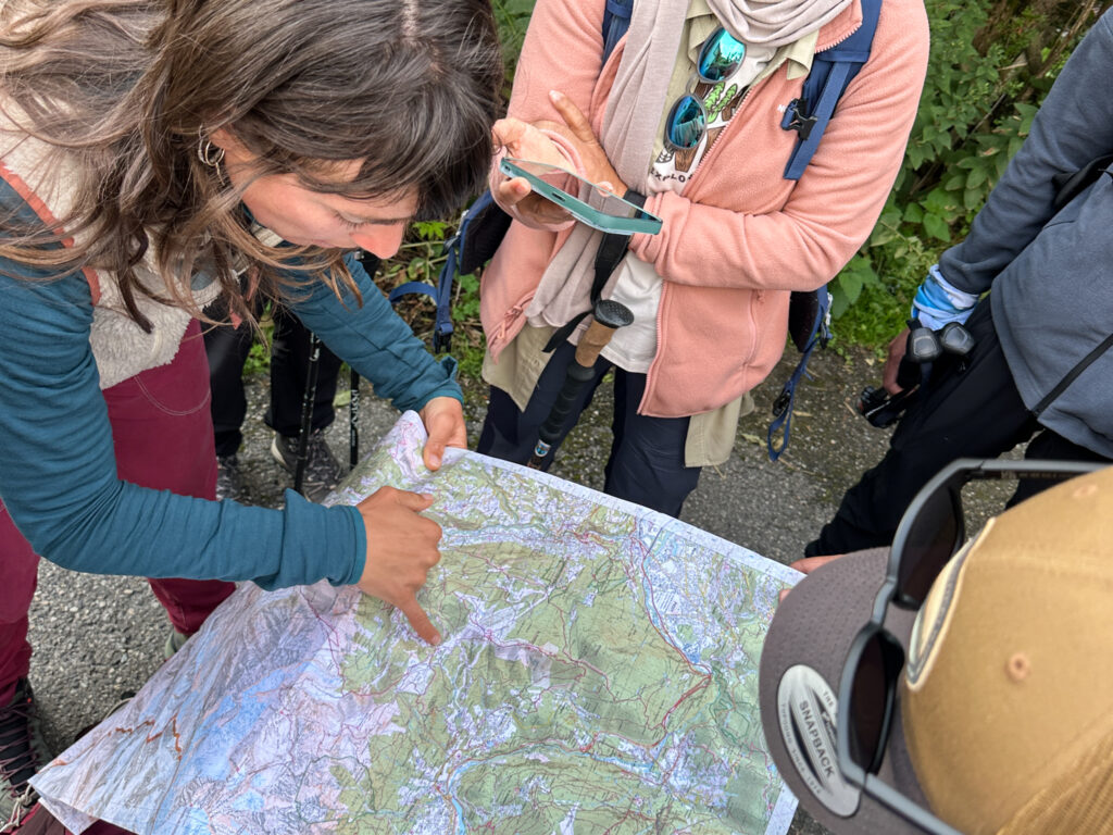 Guided hikers reviewing a Tour du Mont Blanc map before starting a mountain stage