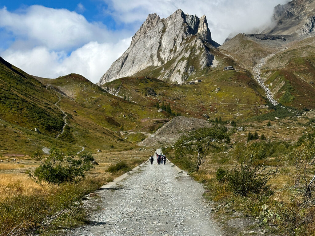 Tour du Mont Blanc hikers walking toward an Alpine pass on a clear mountain trail