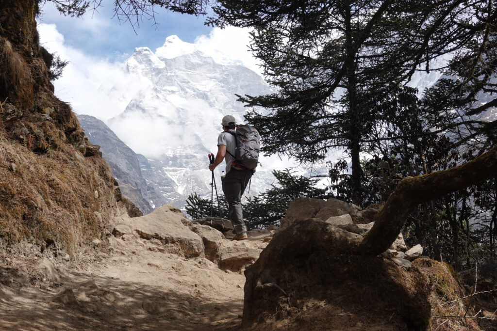 Trekker hiking through a forest trail with Himalayan mountain views in Nepal with Life Happens Outdoors