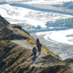Trekkers walking a high alpine trail above a glacial valley on a Chamonix to Zermatt hiking journey