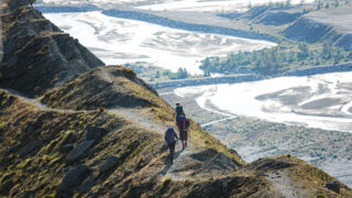 Trekkers walking a high alpine trail above a glacial valley on a Chamonix to Zermatt hiking journey