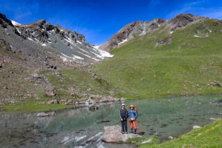 Two trekkers beside an alpine lake on a guided Alps trekking holiday with Life Happens Outdoors