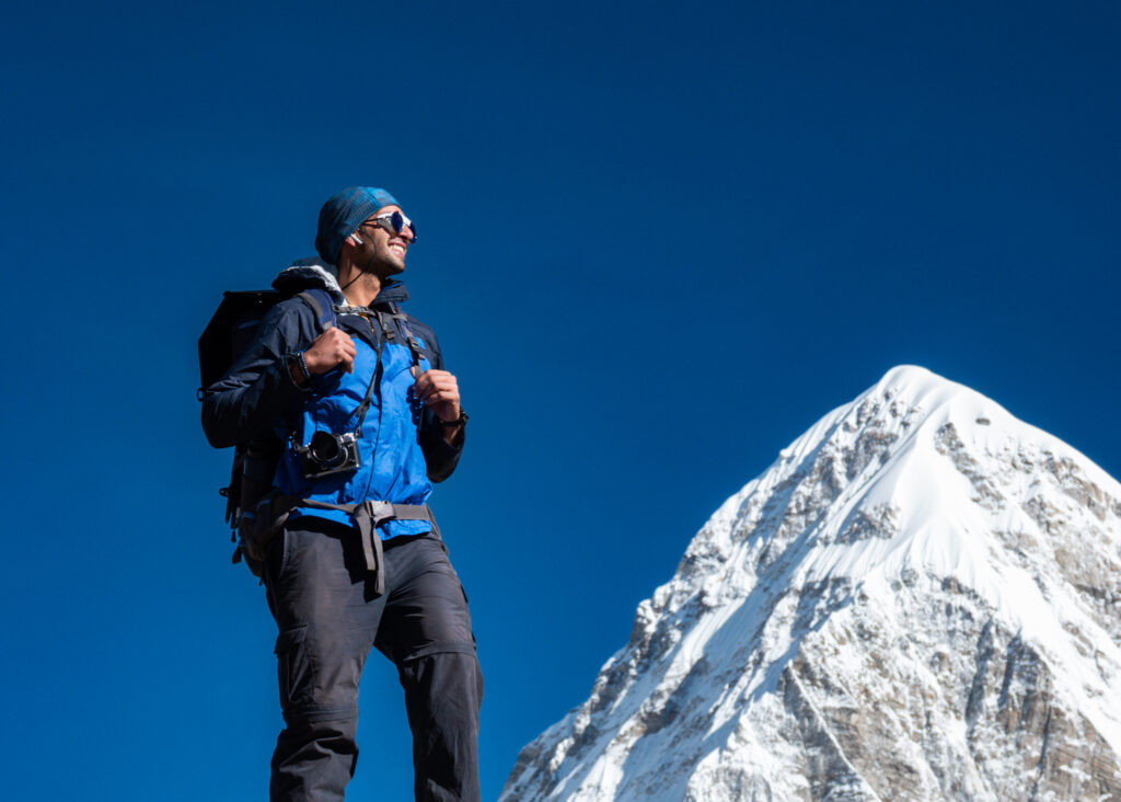 Trekker pausing below a snowy Himalayan peak during a high altitude acclimatisation day