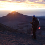 Trekker standing at sunrise on Kilimanjaro during a high altitude climb