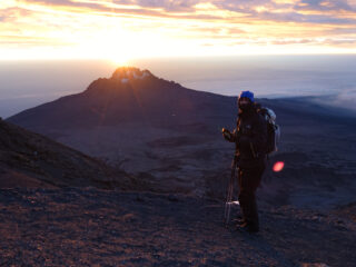 Trekker standing at sunrise on Kilimanjaro during a high altitude climb