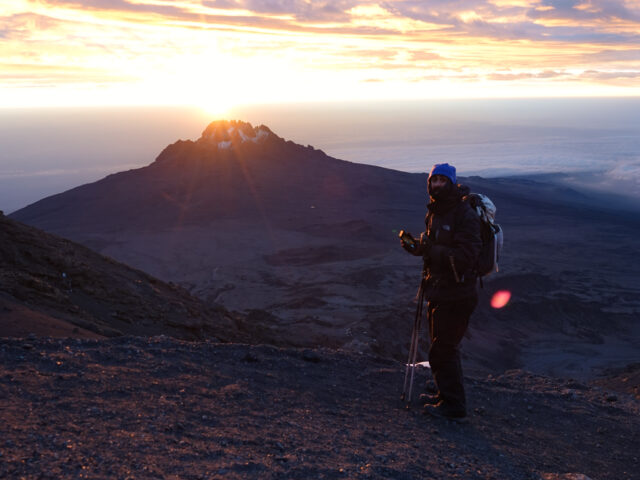 Trekker standing at sunrise on Kilimanjaro during a high altitude climb