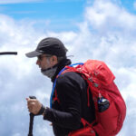 Trekker using a hydration pack while climbing Kilimanjaro above the clouds
