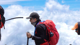 Trekker using a hydration pack while climbing Kilimanjaro above the clouds