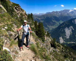 Trekker on an exposed alpine trail showing the rough mountain terrain of the Walker’s Haute Route