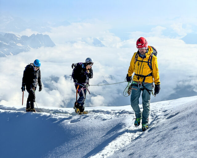 Roped climbers ascending a snowy ridge during a guided Mont Blanc climb.