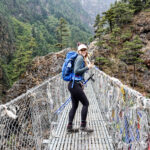Trekker crossing a suspension bridge on the lower trail shared by the Everest Base Camp and Gokyo Lakes routes in Nepal.