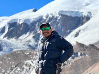 Hari Budha Magar standing in front of snow covered mountains during the Life Happens Outdoors Aconcagua Expedition.