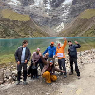 Life Happens Outdoors hiking group beside an alpine lake during a high altitude mountain trek.