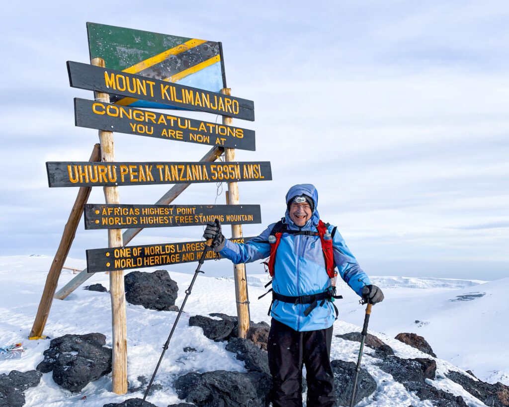 Trekker at Uhuru Peak on Mount Kilimanjaro after completing the high altitude summit climb