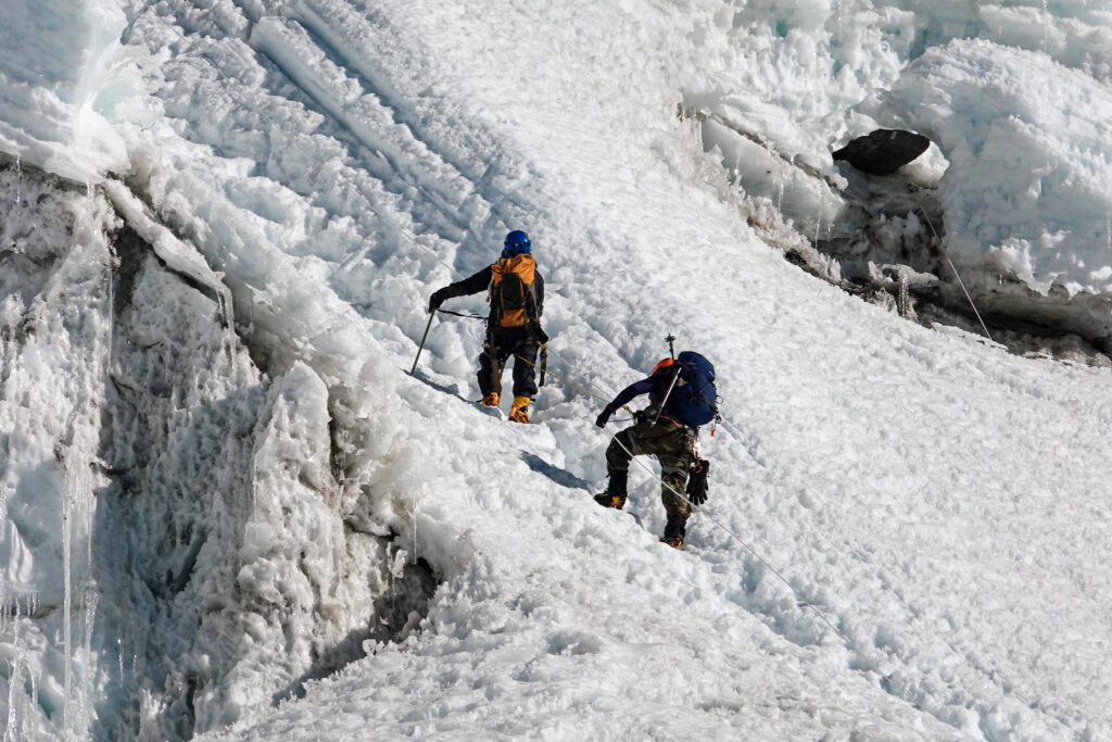 Two climbers using ropes to move through steep glacier terrain on Island Peak in Nepal
