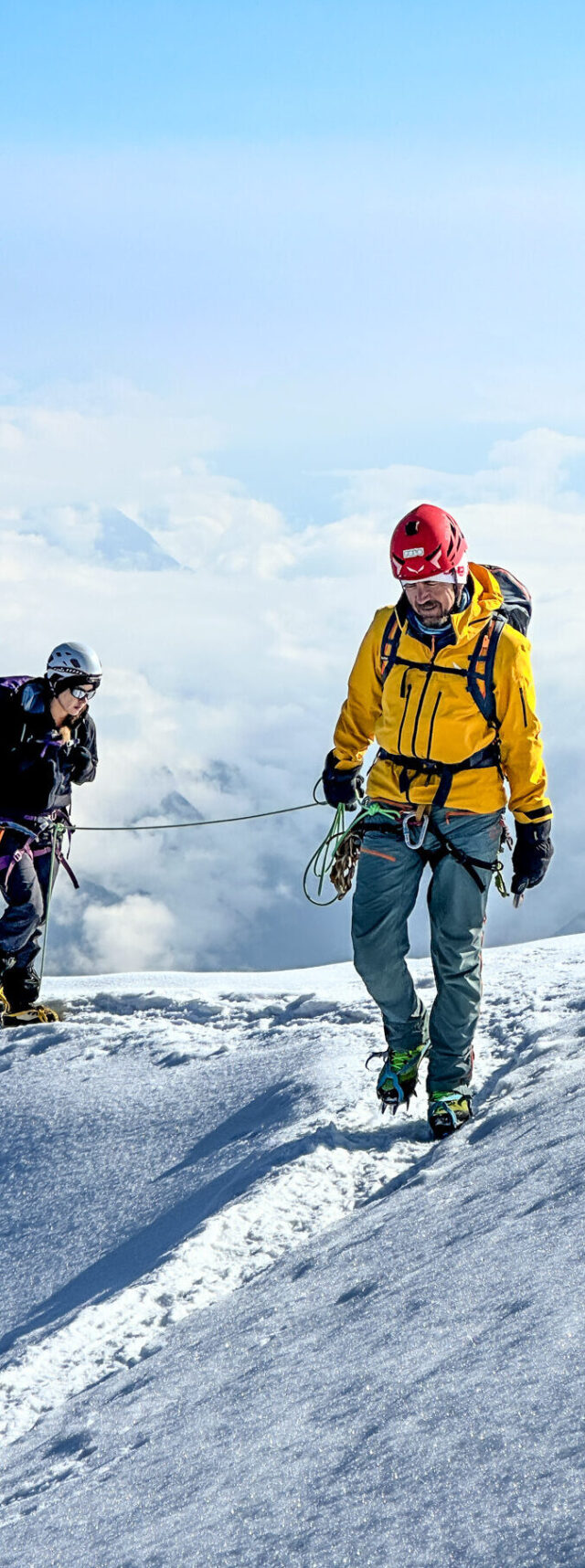 Three roped climbers moving above the clouds on a snow-covered Mont Blanc route.