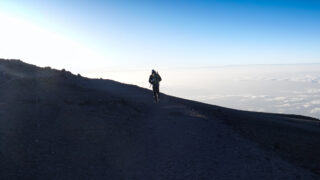 A lone trekker walking above the clouds on Kilimanjaro during the Moving Mountains documentary project.