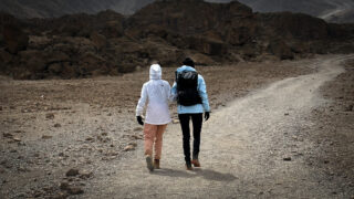 Raneem Faraidy assisted by a trekker walking together through Kilimanjaro’s high altitude landscape during the Moving Mountains documentary.